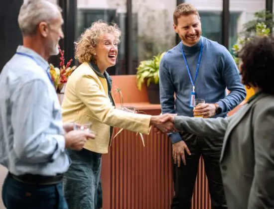 Business people smiling and shaking hands representing how a donor feels when thanked by a charity using SmartThank